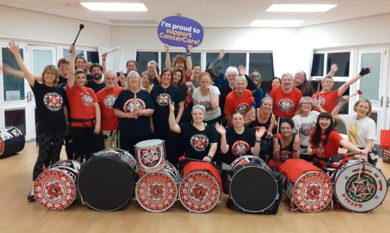 Batala drummers holding a sign which says I'm supporting Cancer Care