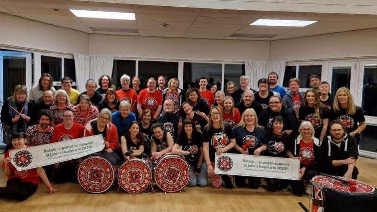 Batala Lancaster holding banners supporting St Johns Hospice